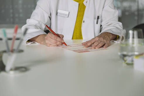 Doctor sitting at desk filling out prescription - MFF05503