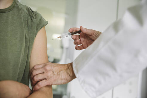 Doctor injecting vaccine into arm of teenager - MFF05510