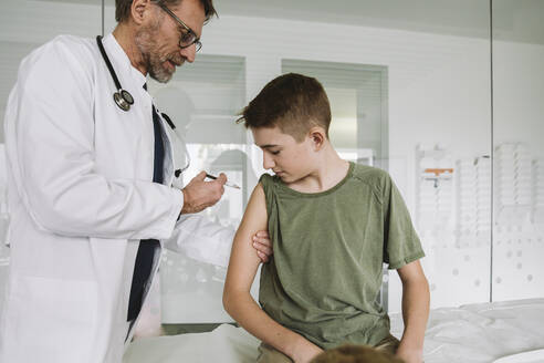 Arzt injiziert einem Teenager einen Impfstoff in den Arm - MFF05517