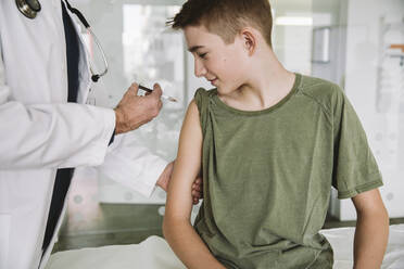 Arzt injiziert einem Teenager einen Impfstoff in den Arm - MFF05518