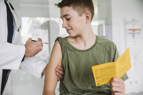 Doctor injecting a vaccine into teenager’s arm stock photo