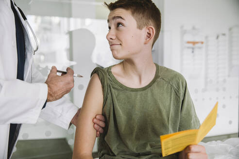 Doctor injecting a vaccine into teenager’s arm - MFF05520