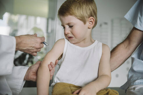Pediatrist injecting vaccine into arm of unhappy toddler - MFF05523