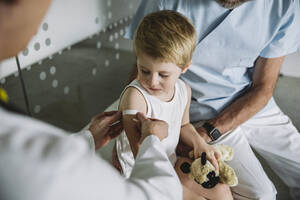 Pediatrist putting band-aid onto arm of toddler after vaccination - MFF05527