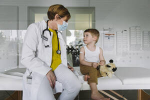 Kinderarzt mit Gesichtsmaske und Kleinkind in einer Arztpraxis - MFF05532