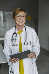 Portrait of smiling doctor holding tablet - MFF05551