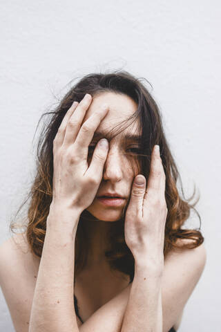 Portrait of depressed young woman with hands on her face stock photo