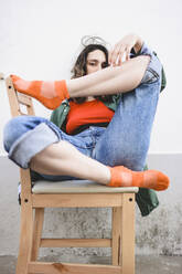 Junge Frau sitzt auf einem Stuhl im Freien - FVSF00079