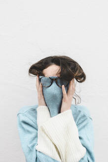 Junge Frau bedeckt ihr Gesicht mit einem Rollkragenpullover - FVSF00086