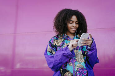 Young woman typing on smartphone and listening to music - TCEF00469