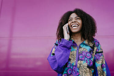 Lächelnde Frau am Telefon, rosa Wand im Hintergrund - TCEF00472