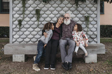 Portrait of grandparents sitting with cute twin grandchildren outside - CAVF79012