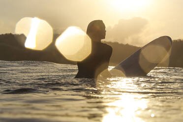 Weibliche Surferin im Meer bei Sonnenuntergang - CAVF79024