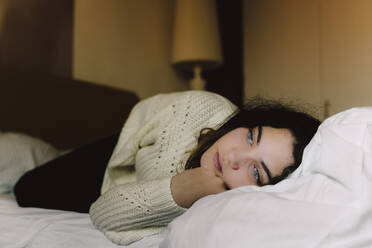 Porträt eines nachdenklichen Mädchens, das auf dem Bett liegt und in die Ferne schaut - ERRF03391