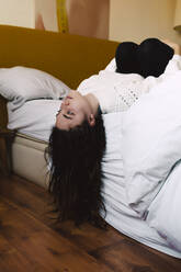 Porträt eines nachdenklichen Mädchens, das auf dem Bett liegt und in die Ferne schaut - ERRF03393
