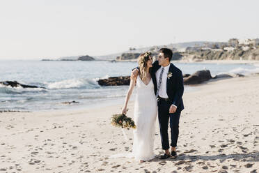 Happy bridal couple walking at the beach - LHPF01242