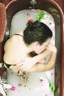 Woman taking a milk bath with blossoms - ERRF03396