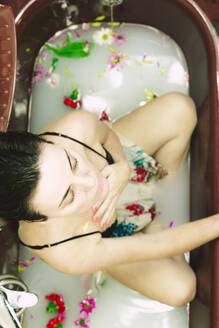 Woman taking a milk bath with blossoms - ERRF03397