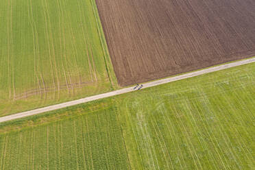 Germany, Baden-Wurttemberg, Remshalden, Aerial view of two cyclists riding along countryside dirt road in spring - WDF05940