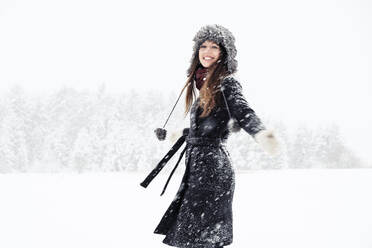 Porträt einer glücklichen jungen Frau, die in einer Winterlandschaft tanzt - WFF00299
