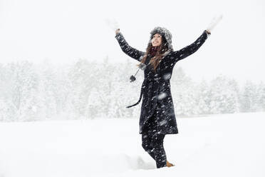 Porträt einer glücklichen jungen Frau, die in einer Winterlandschaft tanzt - WFF00301