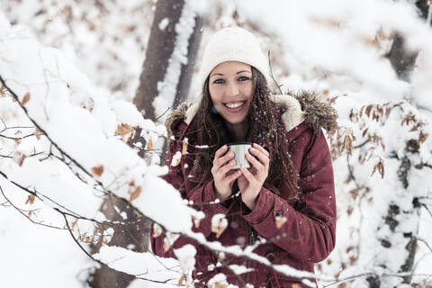 Porträt einer glücklichen jungen Frau mit heißem Getränk im Winter, lizenzfreies Stockfoto