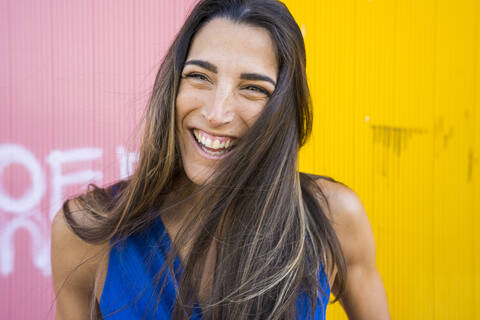 Young smiling woman in front of pink and yellow wall stock photo