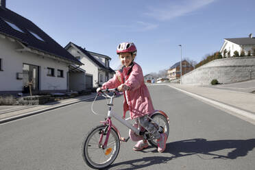 Porträt eines kleinen Mädchens mit Fahrrad in einem Wohngebiet - KMKF01270