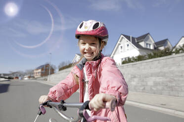 Porträt eines glücklichen kleinen Mädchens mit Fahrrad in einem Wohngebiet - KMKF01271