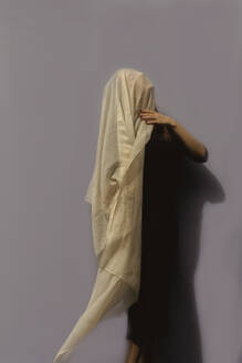 Woman under cloth in front of gray wall - ERRF03417