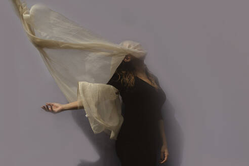 Woman under cloth in front of gray wall - ERRF03418