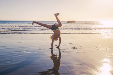 Little boy practicing handstand on the beach - IHF00320