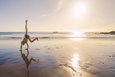 Little boy practicing handstand on the beach - IHF00321