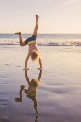 Little boy practicing handstand on the beach - IHF00324