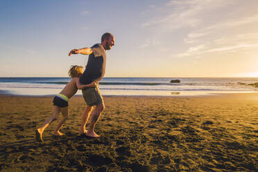 Vater und Sohn spielen und laufen am Strand - IHF00325