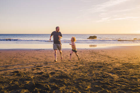 Vater und Sohn spielen und laufen am Strand, lizenzfreies Stockfoto