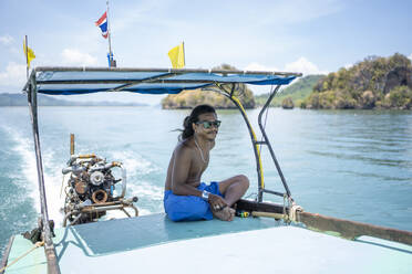 Young native man on a boat trip, Ko Yao Yai, Thailand - FBAF01445