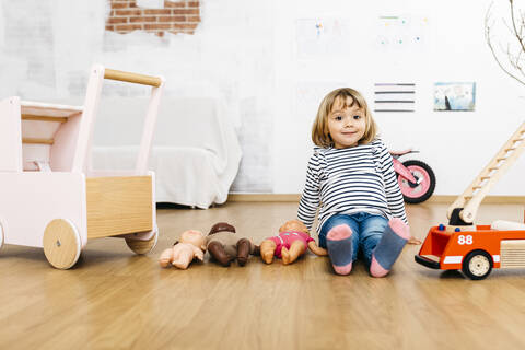 Kleines Mädchen sitzt mit ihrem Spielzeug auf dem Boden, lizenzfreies Stockfoto