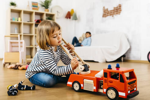 Kleine Blondine spielt mit einem Feuerwehrauto aus Holz - JRFF04318