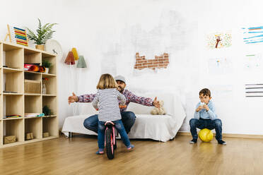 Vater, Tochter und Sohn spielen im Spielzimmer und genießen die freie Zeit - JRFF04321