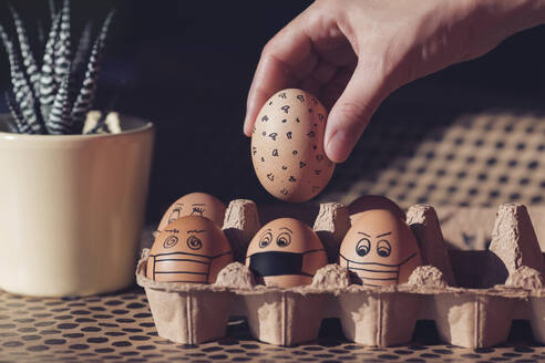 Easter eggs with face masks in a cardboard box - MOMF00843