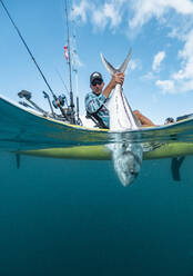 Split shot of man in a kayak catching a fish - AMUF00039
