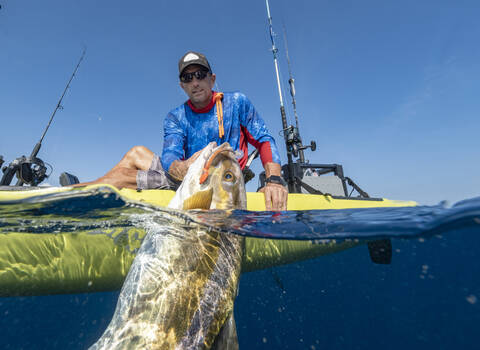 Split shot of man in a kayak catching a fish stock photo