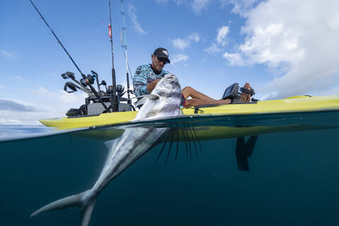 Split shot of man in a kayak catching a fish stock photo