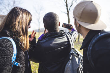 Gruppe von Freunden nimmt Selfie in einem Park auf, Rückansicht - MEUF00407