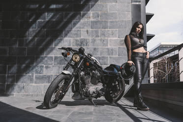 Sexy junge Frau mit Motorradhelm, neben ihrem Motorrad stehend - DAMF00337