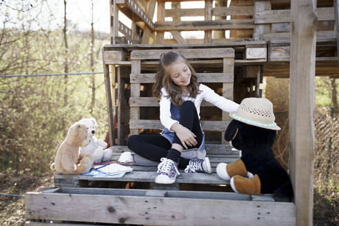 Mädchen spielt mit ihren Teddybären im Baumhaus - HMEF00878