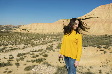 Woman shaking her hair in desertic landscape of Bardenas Reales, Arguedas, Navarra, Spain - XLGF00007