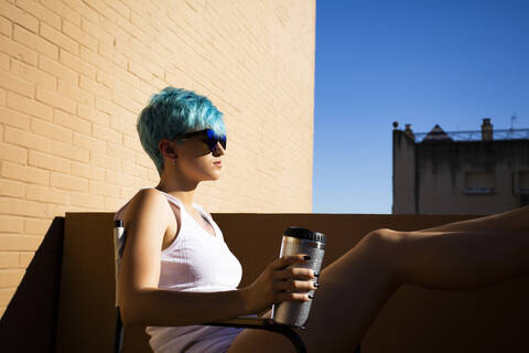 Androgyne junge Frau mit blauem Haar auf dem Balkon, lizenzfreies Stockfoto