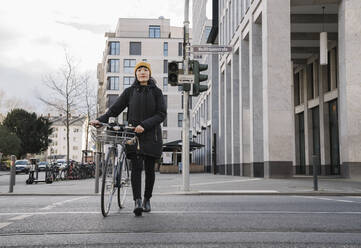 Frau mit Fahrrad in der Stadt unterwegs, Frankfurt, Deutschland - AHSF02212